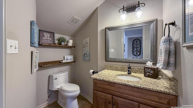 bathroom with vanity, lofted ceiling, and toilet