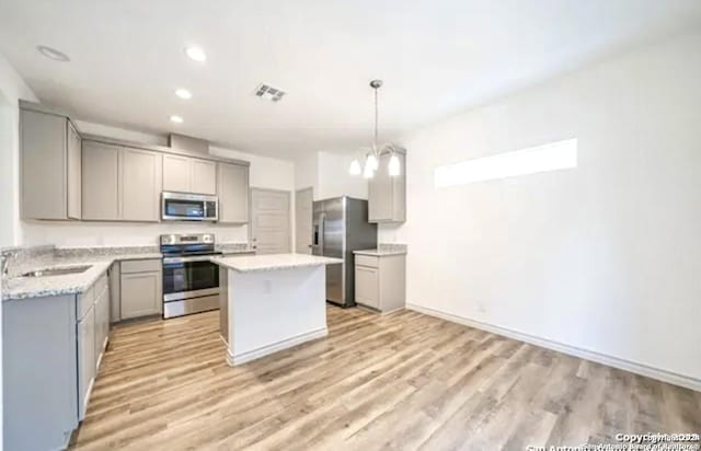 kitchen with stainless steel appliances, gray cabinetry, a chandelier, and a kitchen island