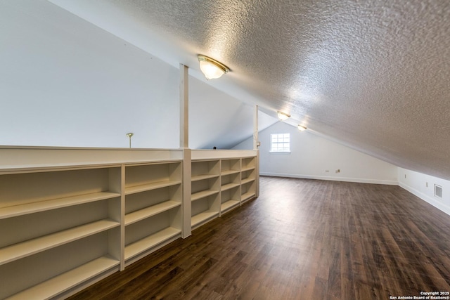 additional living space with lofted ceiling, dark hardwood / wood-style flooring, and a textured ceiling