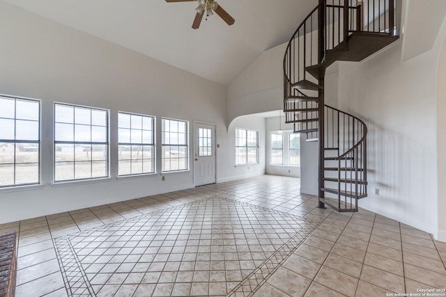 unfurnished living room with ceiling fan, light tile patterned flooring, and a high ceiling