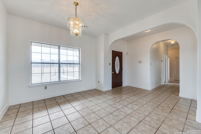 unfurnished room with an inviting chandelier and light tile patterned flooring