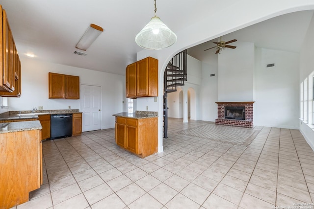 kitchen with ceiling fan, decorative light fixtures, a brick fireplace, light tile patterned flooring, and black dishwasher