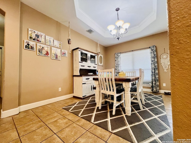 dining room featuring a raised ceiling, a notable chandelier, tile patterned floors, and crown molding