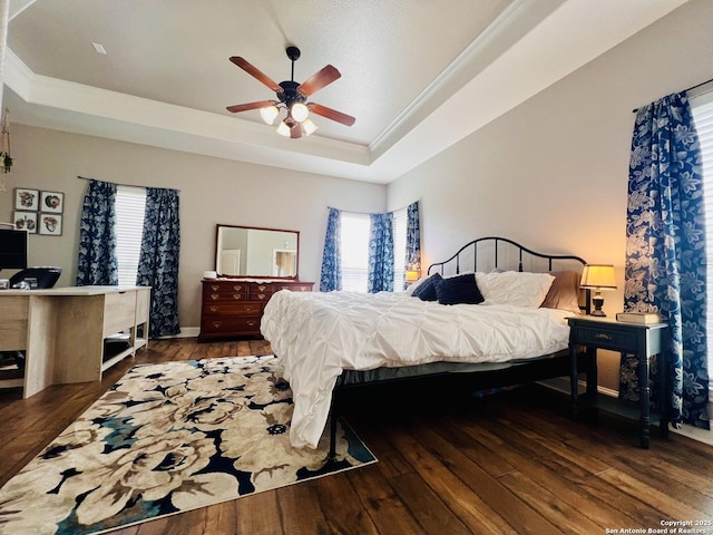 bedroom featuring ceiling fan, dark hardwood / wood-style floors, ornamental molding, and a raised ceiling