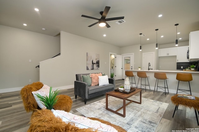 living area with a ceiling fan, visible vents, baseboards, light wood-style flooring, and recessed lighting