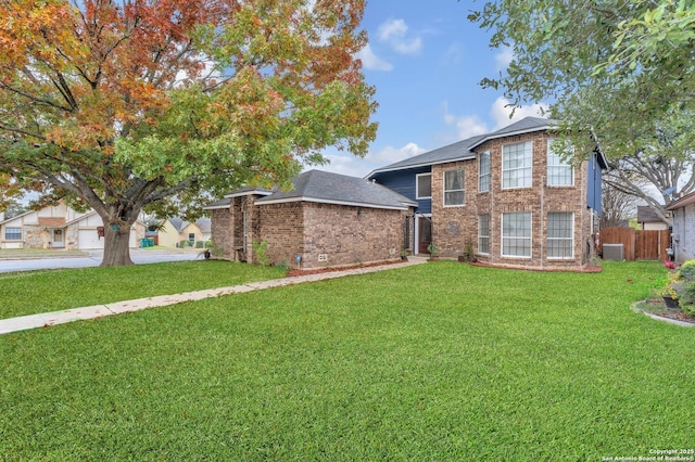 traditional home with a front lawn, central air condition unit, fence, and brick siding