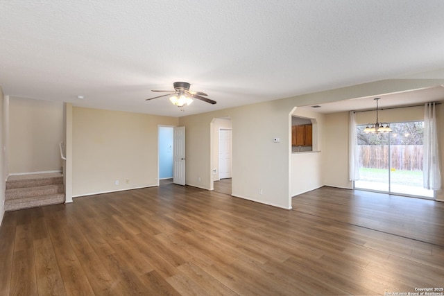 spare room with ceiling fan with notable chandelier, dark wood-type flooring, and a textured ceiling