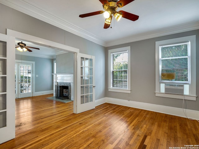 unfurnished living room featuring light wood-type flooring, a fireplace, crown molding, and cooling unit