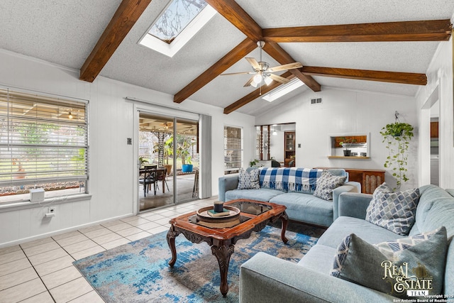 tiled living room with ceiling fan, lofted ceiling with skylight, and a textured ceiling