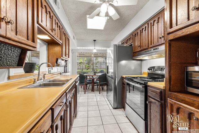 kitchen featuring ceiling fan, pendant lighting, sink, stainless steel appliances, and light tile patterned floors