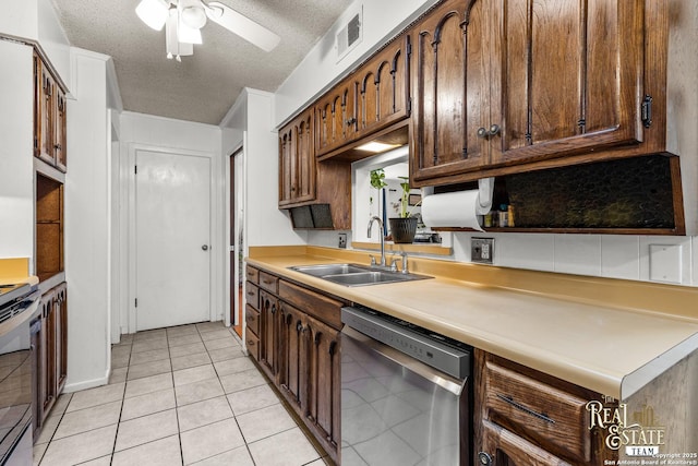 kitchen featuring dishwasher, sink, light tile patterned flooring, stainless steel electric stove, and a textured ceiling