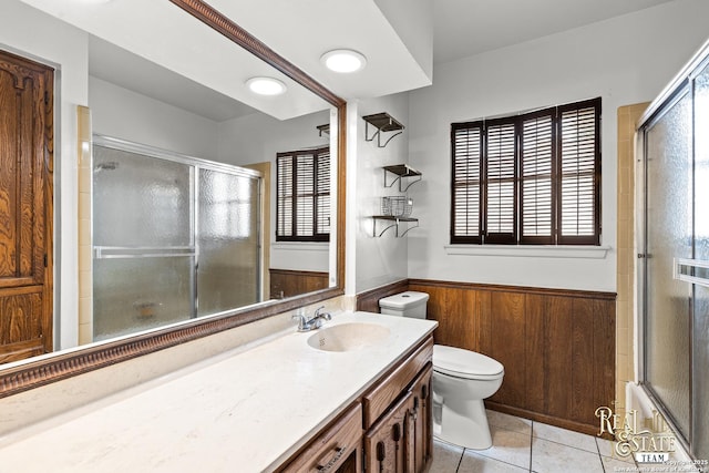 bathroom with tile patterned floors, toilet, vanity, and wood walls