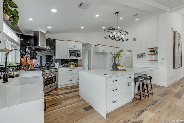 kitchen with appliances with stainless steel finishes, extractor fan, white cabinetry, and a kitchen island