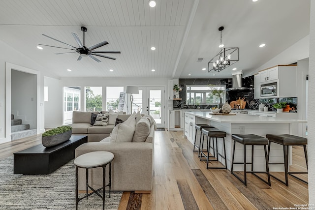 living room featuring vaulted ceiling, ceiling fan with notable chandelier, light hardwood / wood-style floors, and wooden ceiling