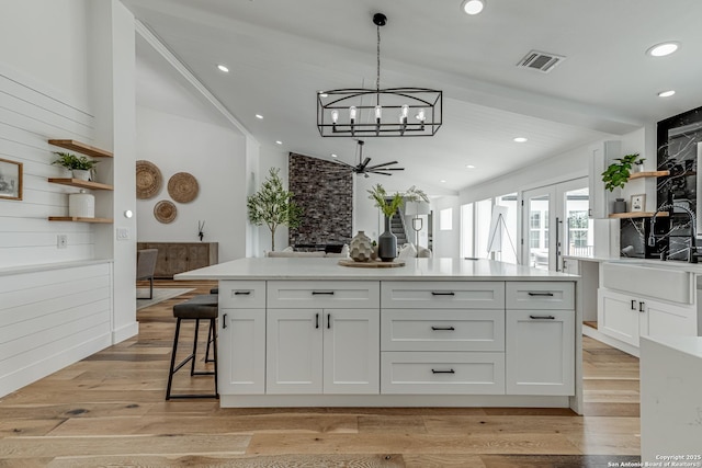 kitchen featuring pendant lighting, white cabinetry, light wood-type flooring, and a kitchen island