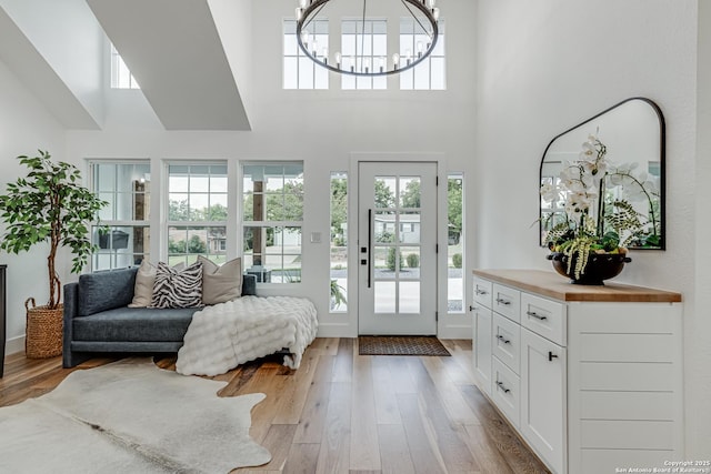 entryway featuring a chandelier, light hardwood / wood-style floors, and a high ceiling