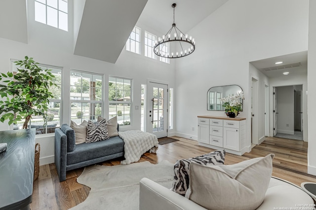 living room featuring a notable chandelier, a high ceiling, and light hardwood / wood-style floors