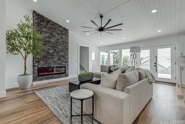 living room featuring wood ceiling, a stone fireplace, ceiling fan, lofted ceiling, and light hardwood / wood-style flooring