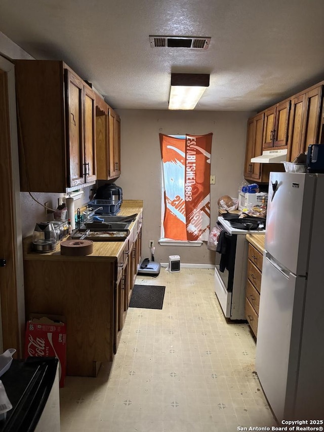 kitchen with white appliances, sink, and a textured ceiling