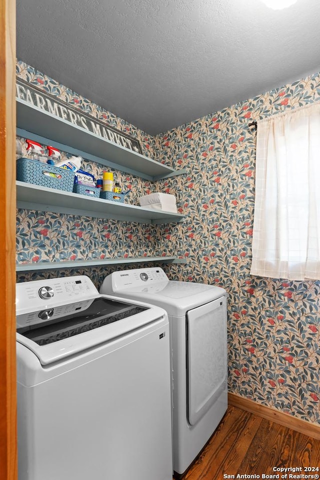 clothes washing area with wallpapered walls, laundry area, wood finished floors, a textured ceiling, and washer and dryer