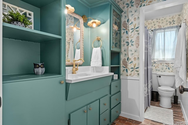 full bathroom with toilet, wallpapered walls, vanity, and wainscoting