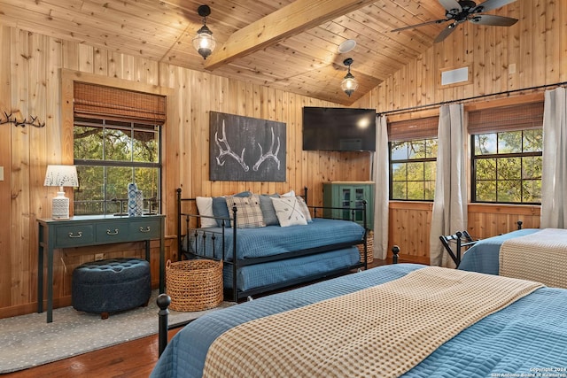 bedroom featuring vaulted ceiling with beams, wood walls, and multiple windows