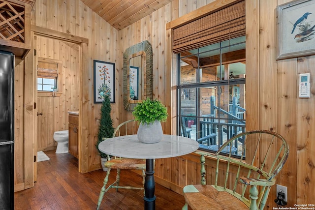 dining space with wood walls, wood ceiling, vaulted ceiling, and hardwood / wood-style flooring