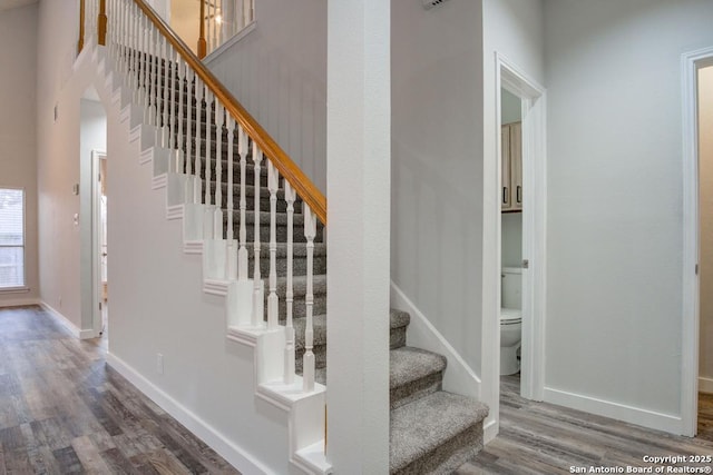 staircase featuring a high ceiling and hardwood / wood-style flooring