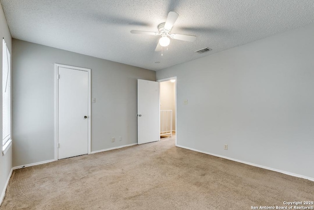 unfurnished bedroom with ceiling fan, a textured ceiling, and light carpet