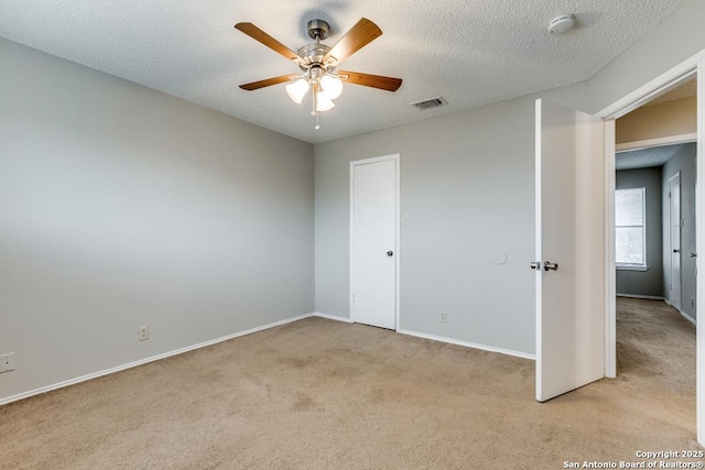 unfurnished bedroom with ceiling fan, a textured ceiling, and light carpet