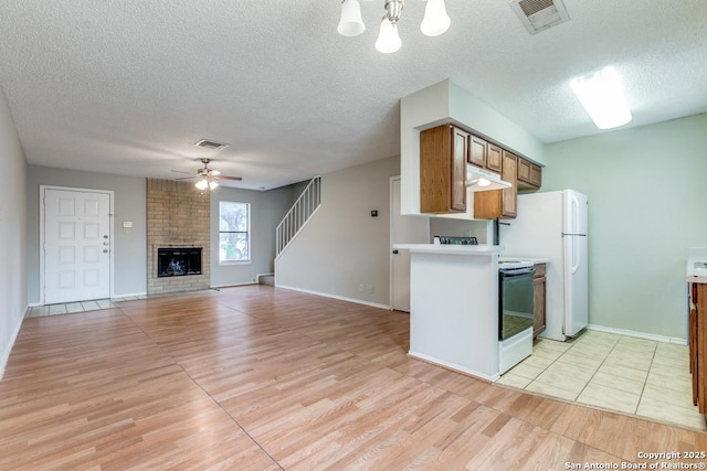 kitchen featuring ceiling fan, a textured ceiling, and a brick fireplace