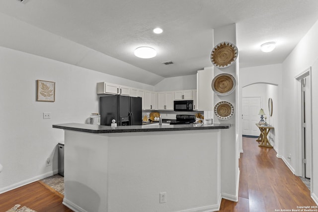 kitchen with vaulted ceiling, black appliances, kitchen peninsula, a textured ceiling, and white cabinets