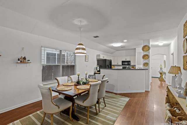 dining space featuring vaulted ceiling and hardwood / wood-style floors