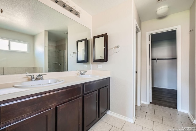 bathroom with vanity, tile patterned flooring, a textured ceiling, and a tile shower