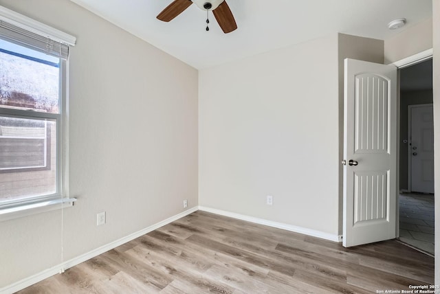 empty room featuring ceiling fan, a healthy amount of sunlight, and light hardwood / wood-style floors