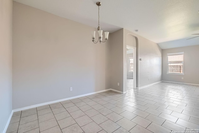 tiled empty room with vaulted ceiling and ceiling fan with notable chandelier