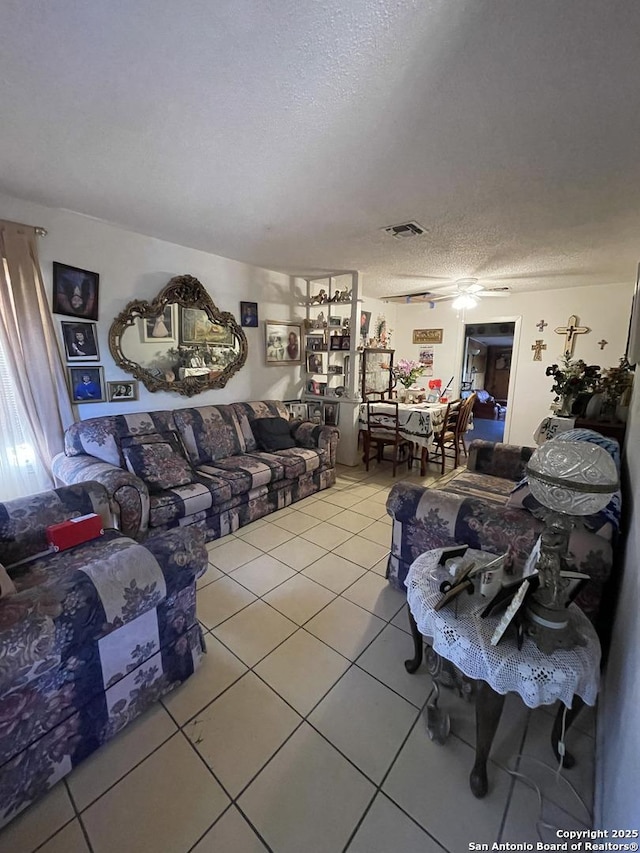 tiled living room with ceiling fan and a textured ceiling