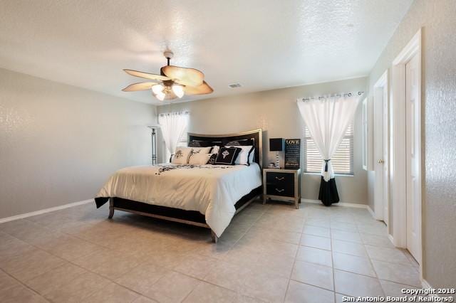 tiled bedroom featuring a textured ceiling, ceiling fan, and multiple windows