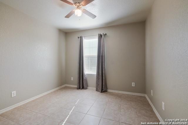 tiled empty room featuring ceiling fan