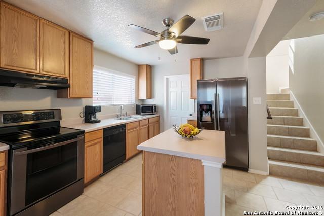 kitchen with ceiling fan, a kitchen island, sink, a textured ceiling, and stainless steel appliances