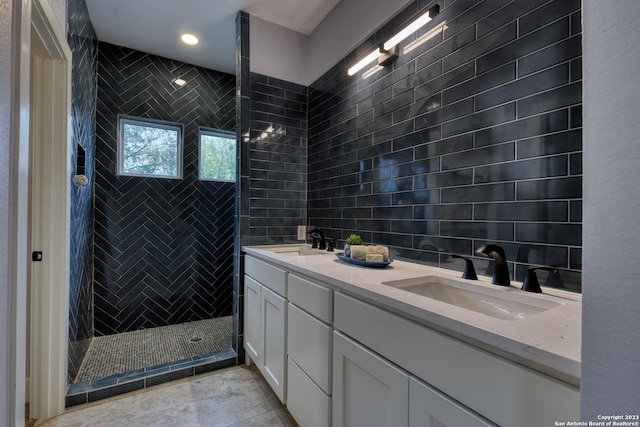 bathroom with a tile shower, vanity, and tile walls