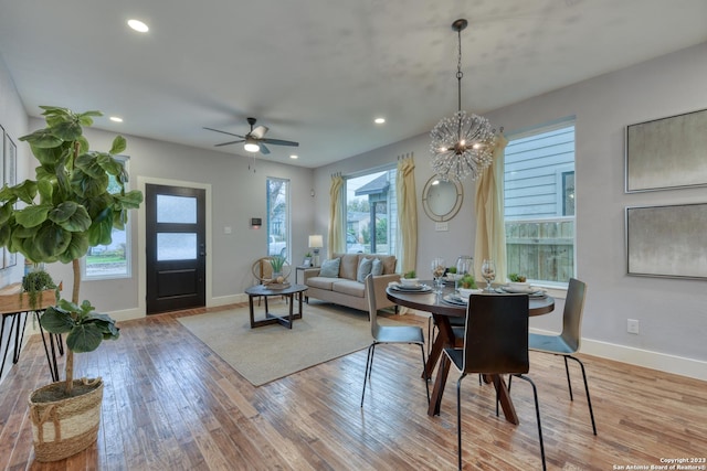 dining area with light hardwood / wood-style floors and ceiling fan with notable chandelier