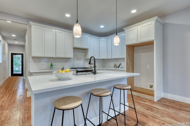 kitchen with light stone countertops, white cabinets, hanging light fixtures, and sink