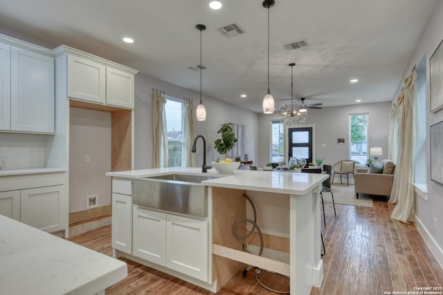 kitchen featuring white cabinetry, ceiling fan, backsplash, hanging light fixtures, and light stone countertops