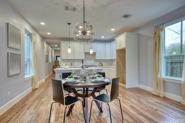 dining space featuring light hardwood / wood-style flooring, an inviting chandelier, and a healthy amount of sunlight