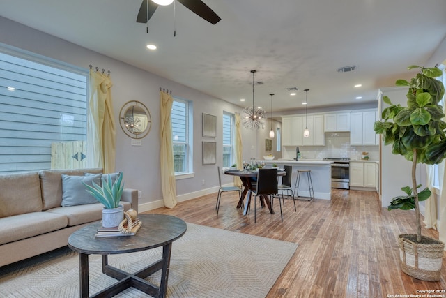 living room featuring ceiling fan, light hardwood / wood-style flooring, and sink