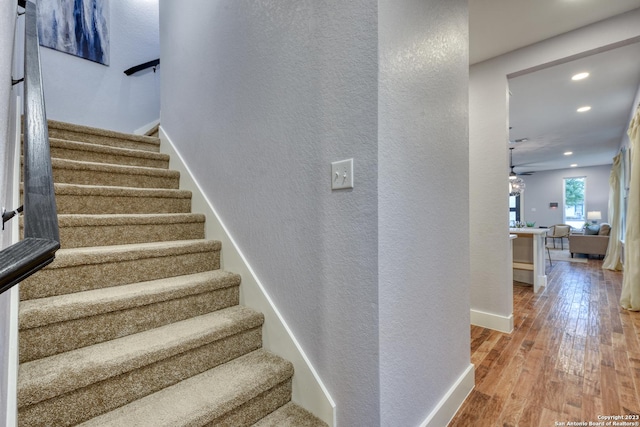 stairs featuring ceiling fan and hardwood / wood-style floors