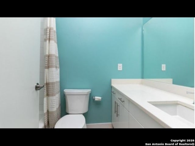 bathroom featuring toilet, vanity, and a shower with shower curtain