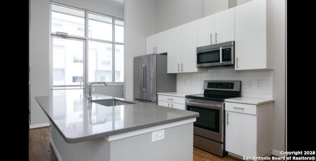 kitchen featuring white cabinetry, appliances with stainless steel finishes, a center island with sink, and sink