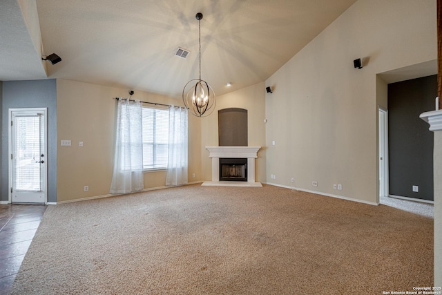 unfurnished living room with a notable chandelier, vaulted ceiling, and carpet flooring